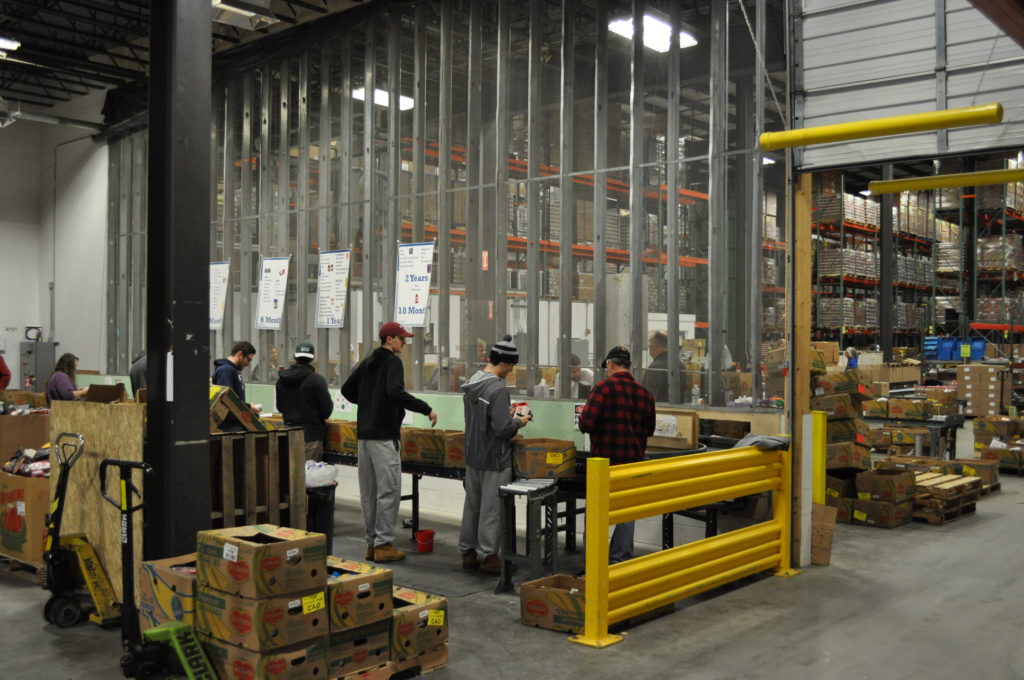Student volunteers from Bates College inspect donated food at the Auburn warehouse.