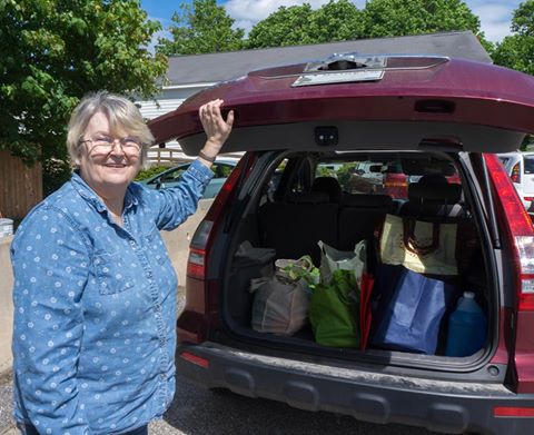 A donor shows her trunk full of totes of food.