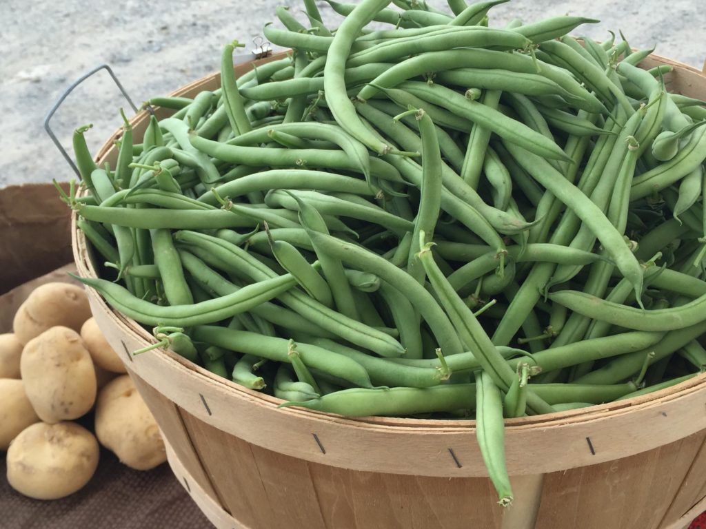 Green beans fill a wooden basket.