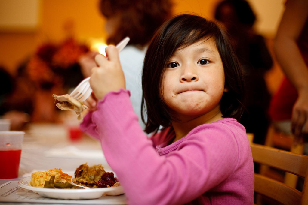 A young girl with her healthy plate of food in front of her.
