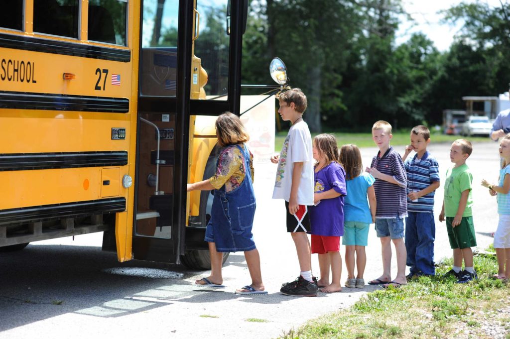 A line of students boarding a school bus.