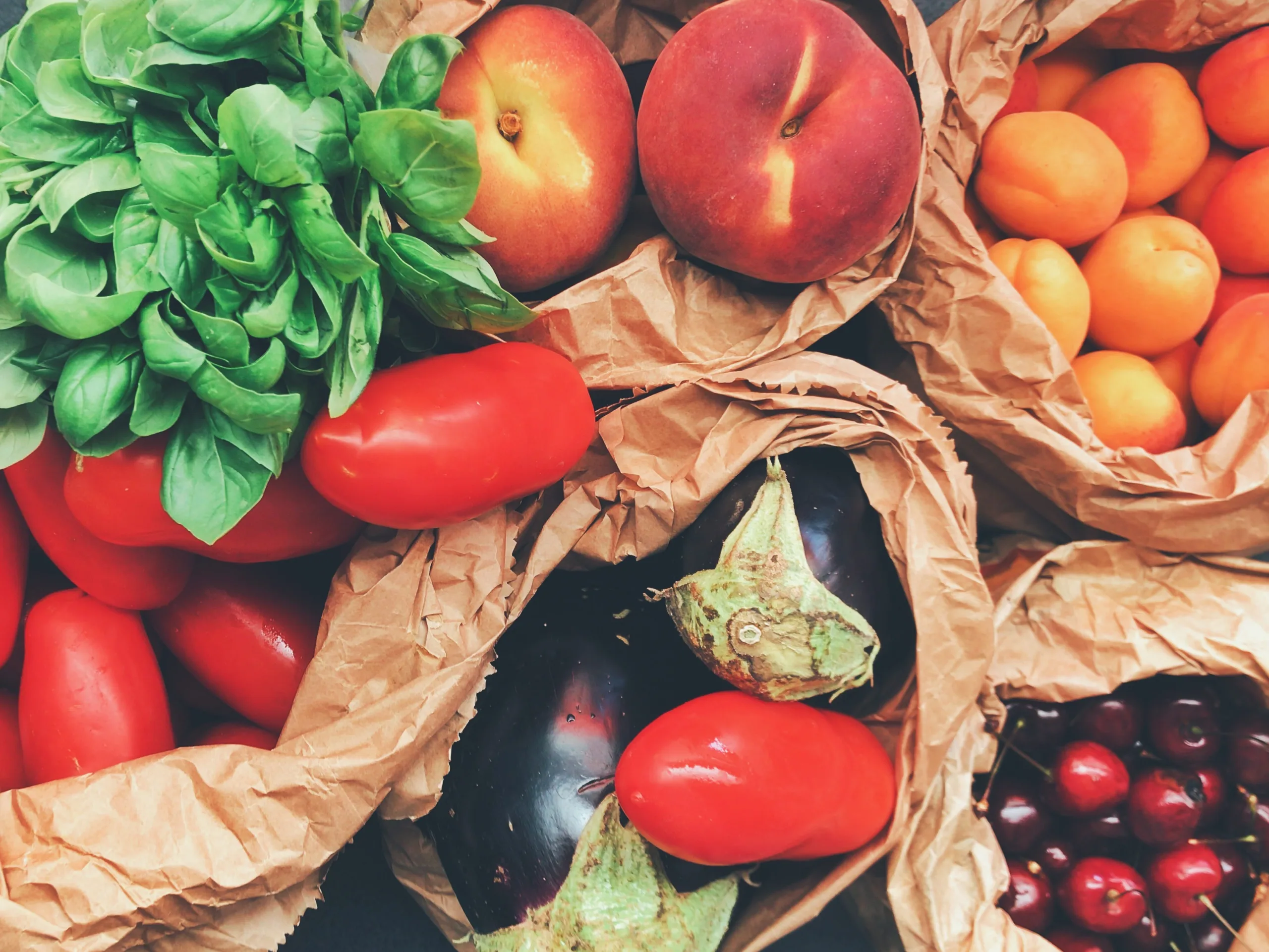 Brown bags containing a variety of fresh produce.
