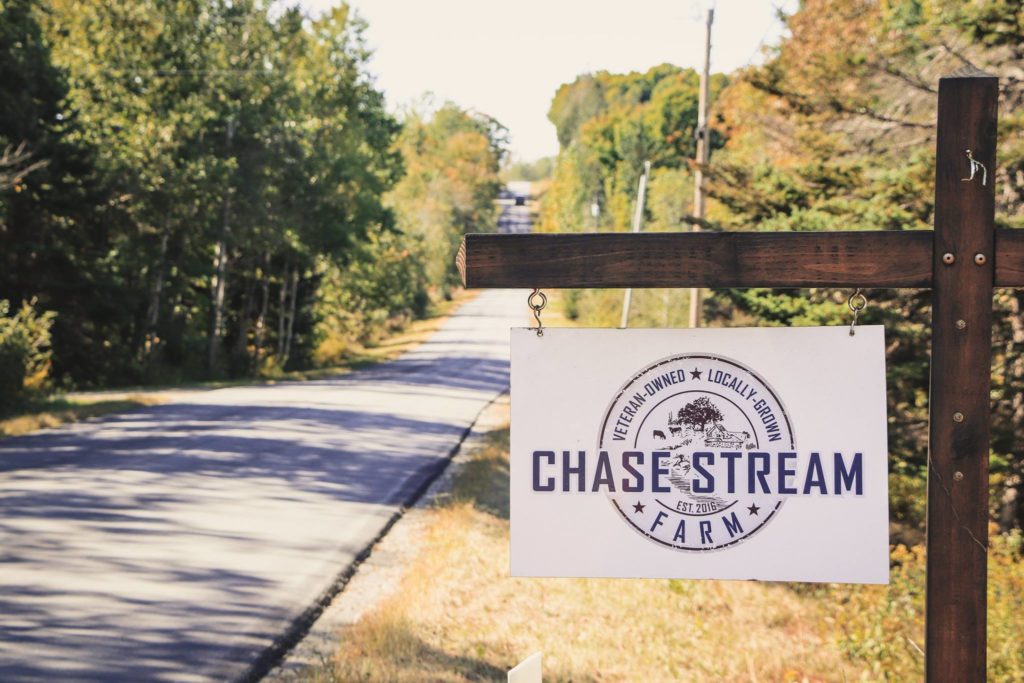 Chase Stream Farm sign with the road in the background.