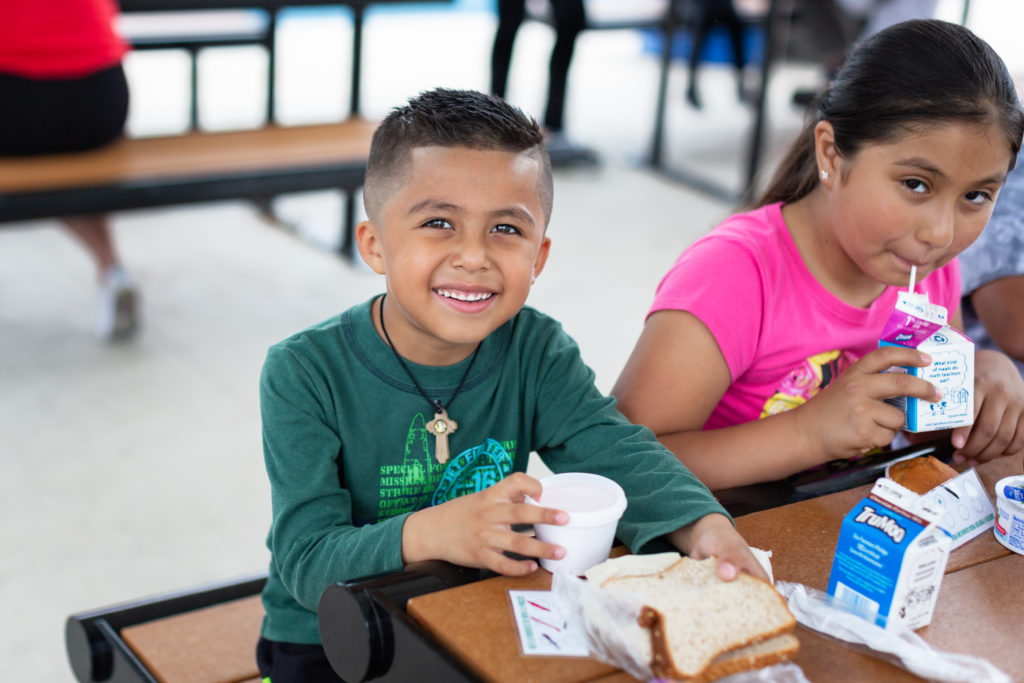 Two young students enjoy their lunch at school.