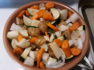 Healthy vegetable medley with carrots, onion, zucchini, and potatoes cooking on the stove.