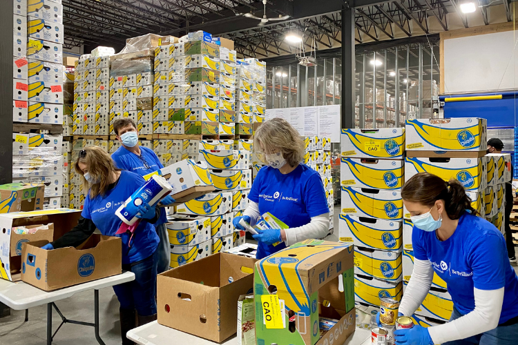 Volunteers at the Auburn Distribution Center - Good Shepherd Food Bank - four volunteers in blue shirts in front of banana boxes