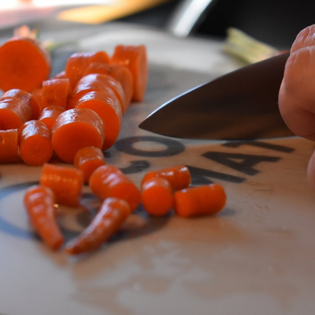 Hands cutting carrots with knife on cooking matters cutting board