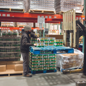 Man in distribution center packing a pallet of cans