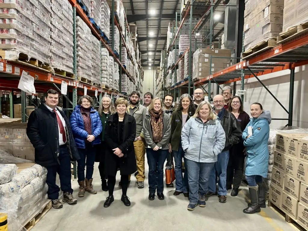 Group of people standing in a Good Shepherd Food Bank distribution center during the Auburn 131st Legislature Tour