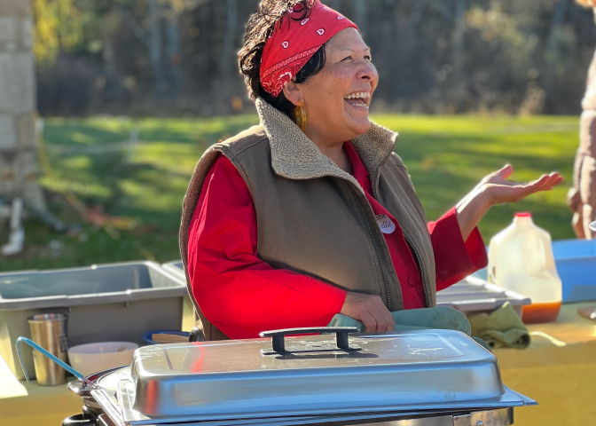 A woman stands excitedly in front of a container of food