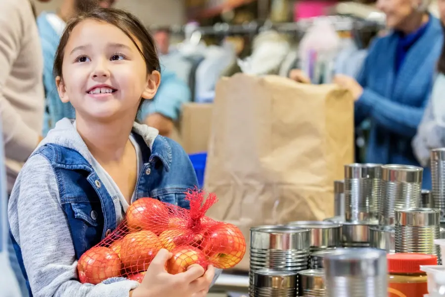 A child smiling as she recieves a Good Shepherd Food Bank Food Donation.