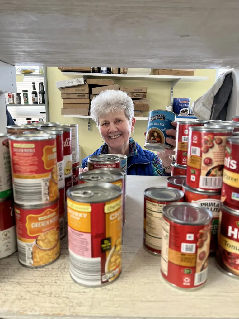 Older Mainer looking through a shelf of canned goods.