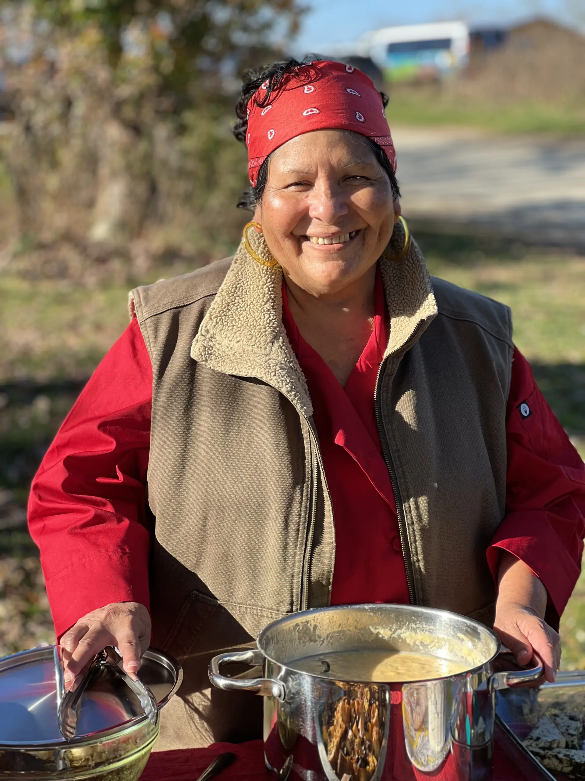 A woman making a pot of soup outside.