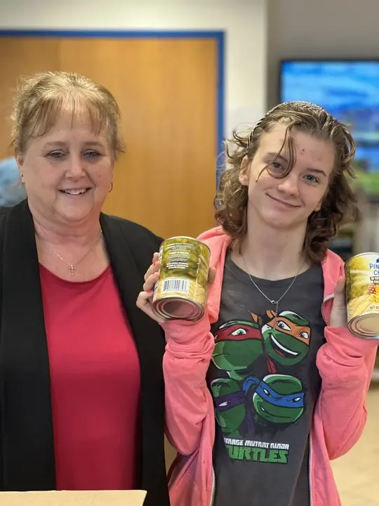 Two ladies holding cans at a food pantry