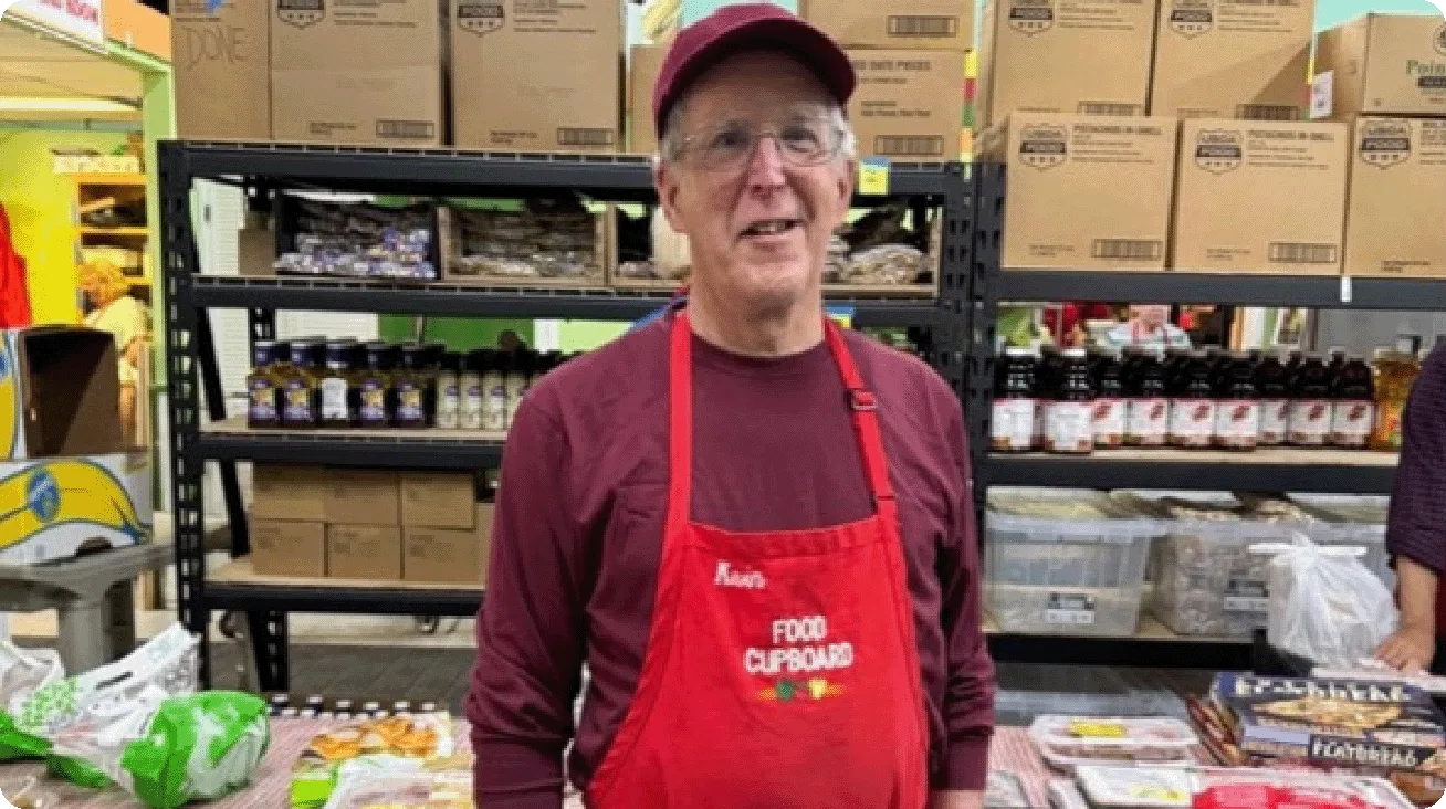 Kevin wears a Food Cupboard apron, ready to package food for distribution.