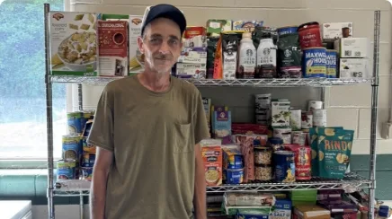 Michael stands in front of shelves full of food that he can choose from for his family.